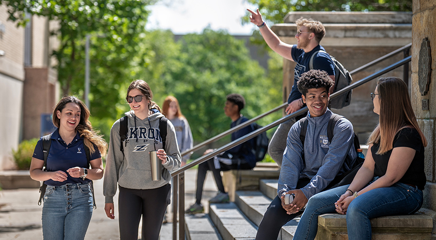 Happy UA students walking out of and in front of Buchtel Hall on The University of ϲʹ campus.